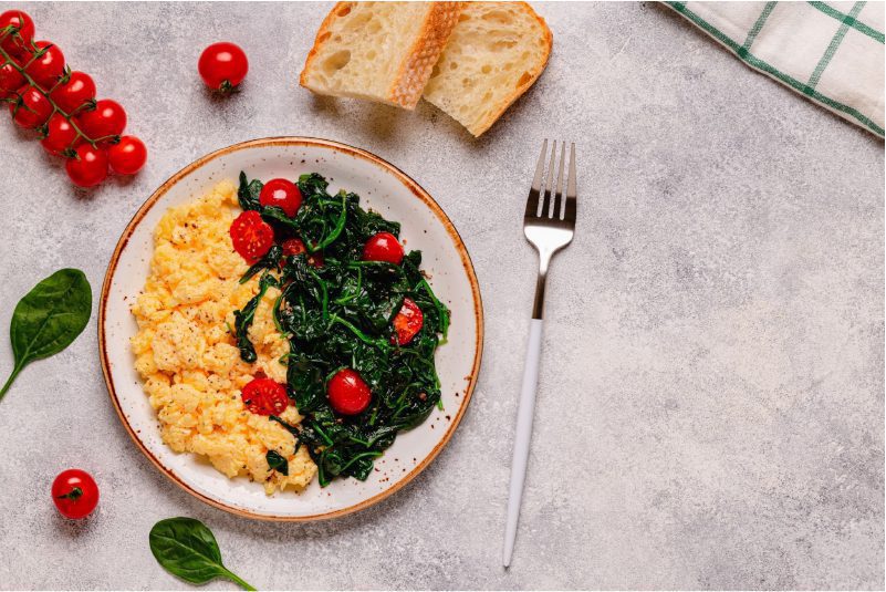 A plate of tofu scramble with spinach and tomatoes