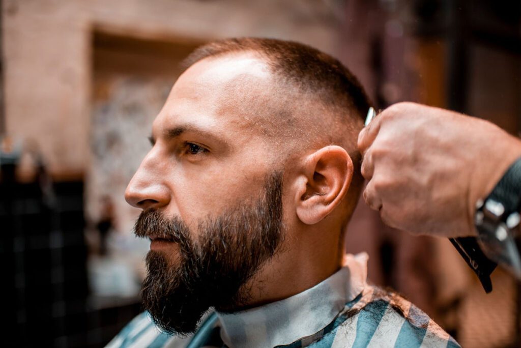 Barber cutting man's hair with buzz clippers