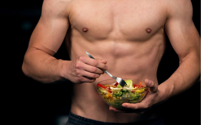 A muscular man holding a plate of healthy food